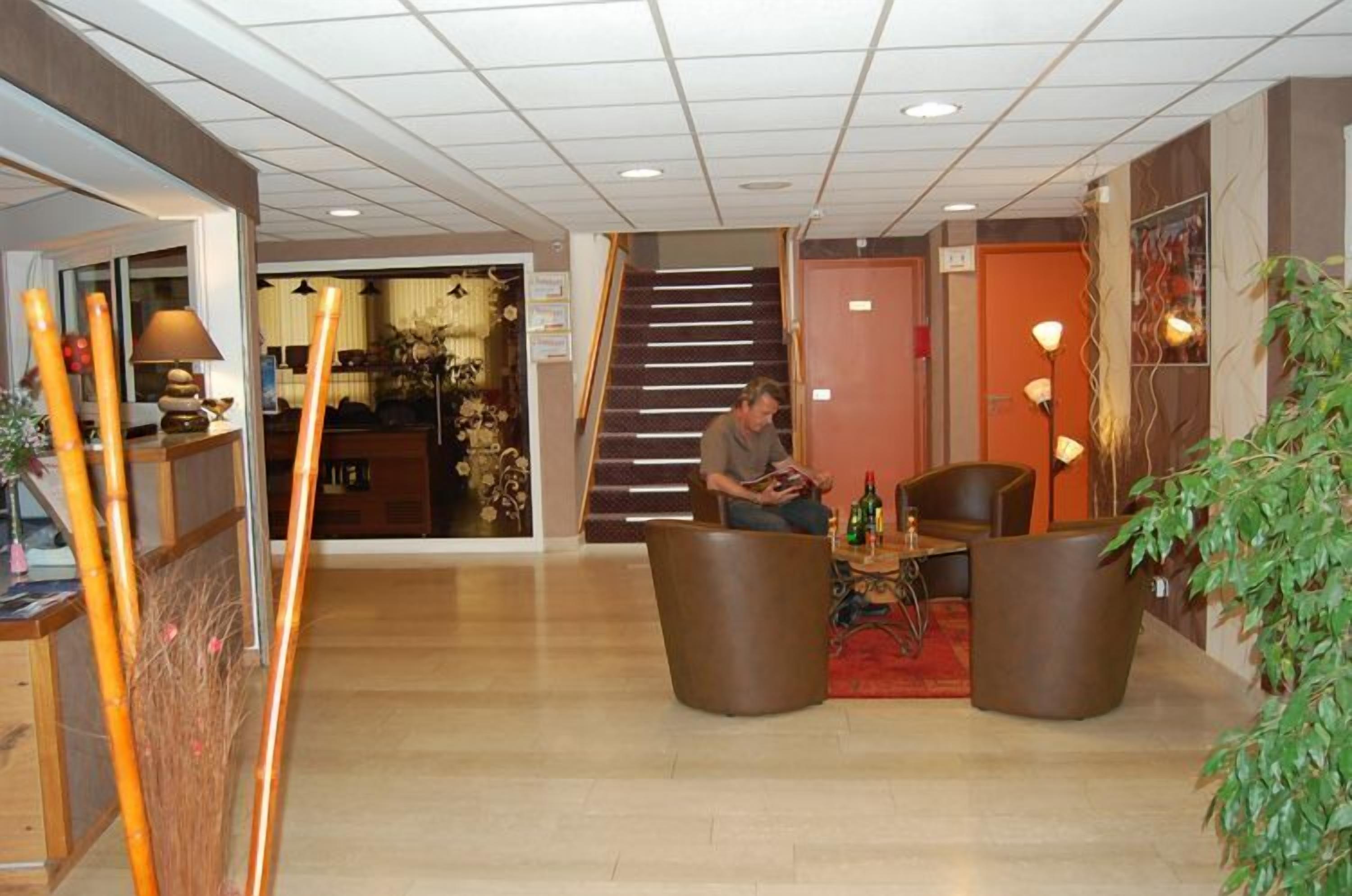 A hotel lobby with a staircase, seating area, and a reception desk.