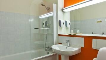 A bathroom with a glass shower enclosure, a white sink, and an orange accent wall.