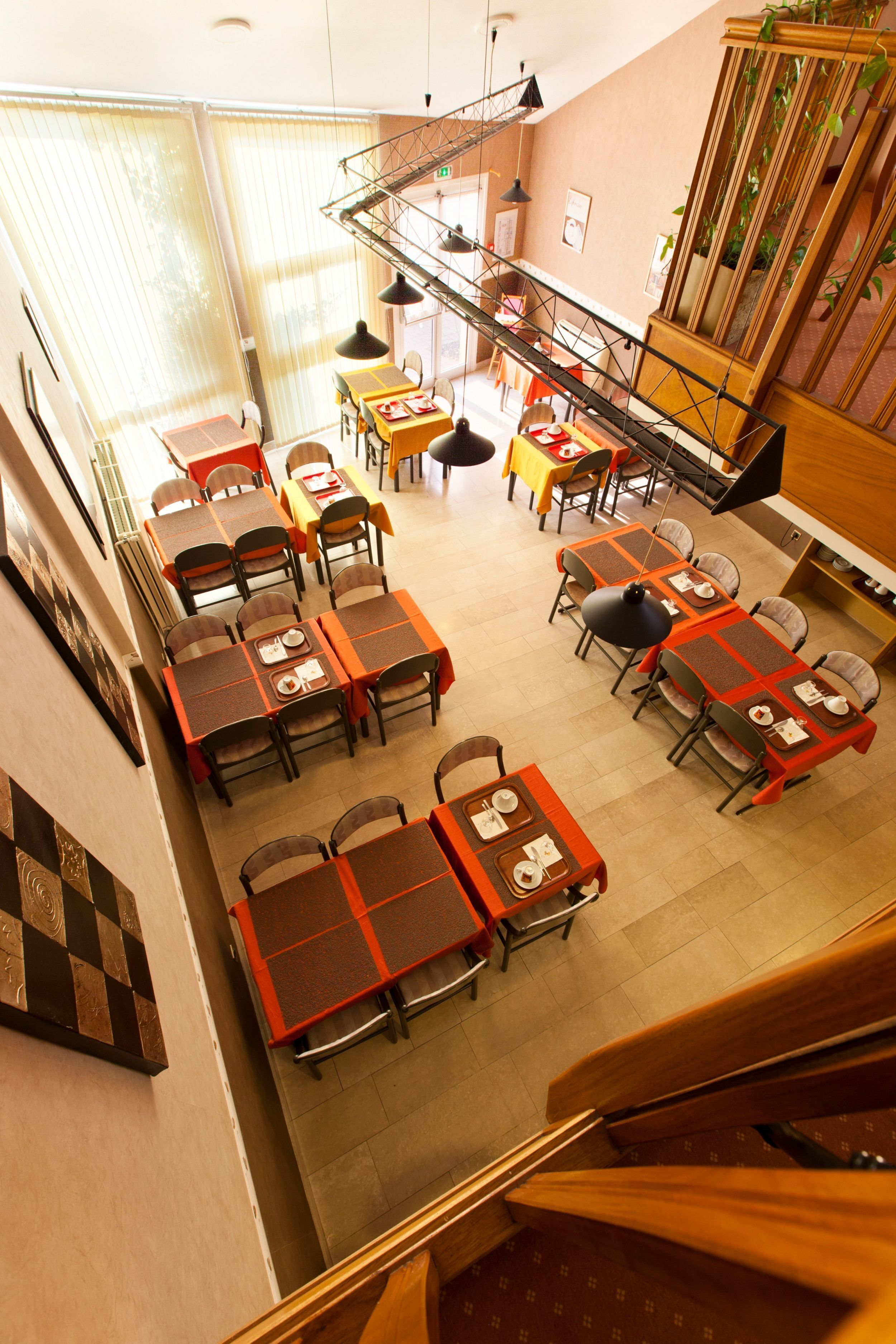 Un comedor con varias mesas y sillas, una escalera y un espejo grande.