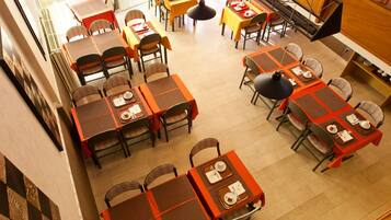 Un comedor con varias mesas y sillas, una escalera y un espejo grande.