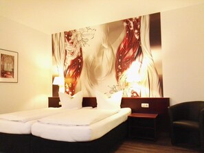 Une chambre d’hôtel avec un grand lit, deux tables de chevet, un bureau et une chaise.