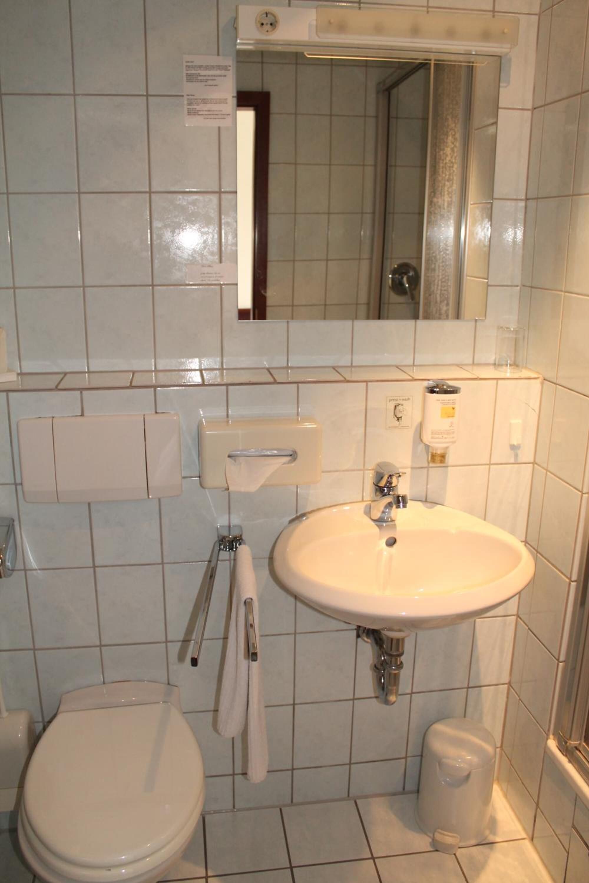 Een badkamer met toilet, wastafel en spiegel.