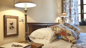 Une chambre d’hôtel avec un lit, une table de chevet avec une lampe, un tableau encadré et une fenêtre avec des rideaux.