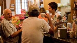 A coffee shop interior with a counter, coffee machines, and various packaged goods on shelves.