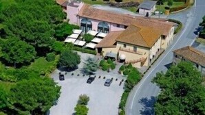 Vue aérienne d’une propriété comprenant un bâtiment principal, un espace de stationnement et des espaces verts environnants.