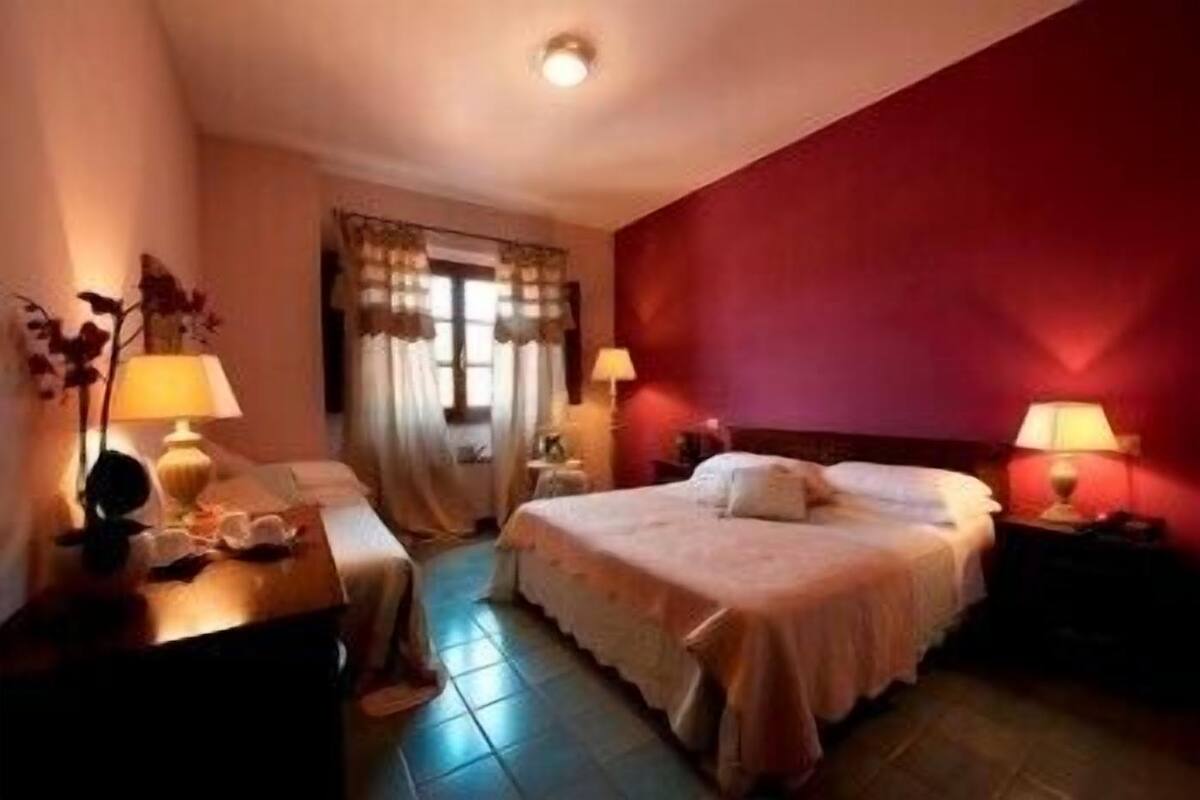 A hotel room with two beds, a desk, and lamps.