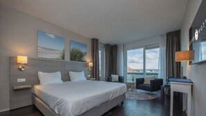 Una habitación de hotel moderna con una cama grande, un escritorio y vistas a la ciudad.