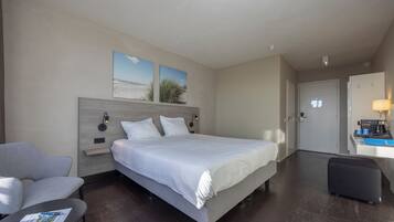 A hotel room with a large bed, a desk with a lamp, a chair, and a small table with a menu.