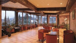 A spacious indoor area with large windows, wooden beams, and several tables and chairs. - Evridika (PAMPOROVO)