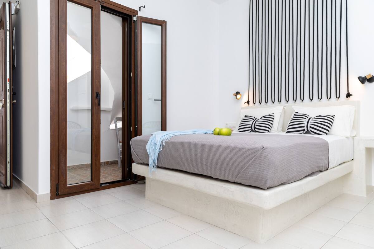 A bedroom with a bed, a sliding door, a wall-mounted light fixture, and a bedspread.