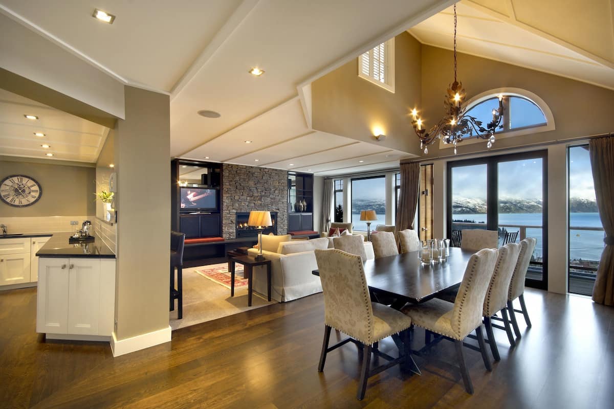 Un amplio salón con una mesa de comedor, asientos cómodos, una chimenea y ventanas grandes con vistas panorámicas.