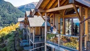 Eine Holzhütte mit einem Balkon mit Blick auf eine gebirgige Landschaft.