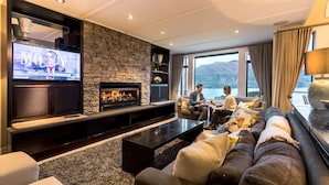Ein modernes Wohnzimmer mit Kamin aus Stein, einem großen Flachbildfernseher und einer Sofagarnitur.