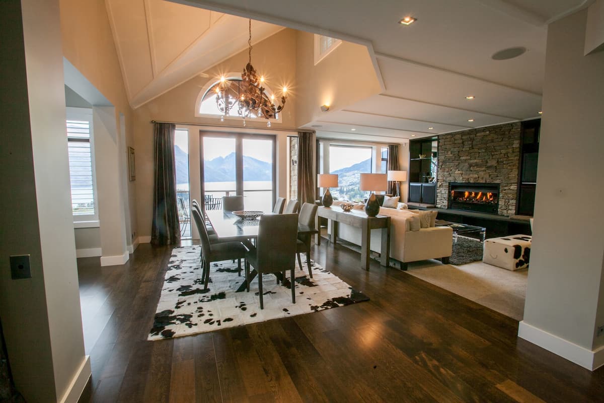 Un amplio salón con una mesa de comedor, sillas, chimenea y vistas a las montañas.