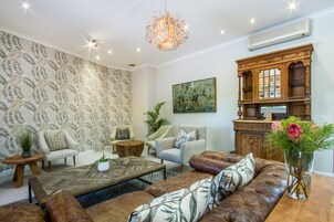 Una sala de estar moderna con un papel tapiz estampado, una mesa de centro de madera, un sofá de cuero y un mueble decorativo.