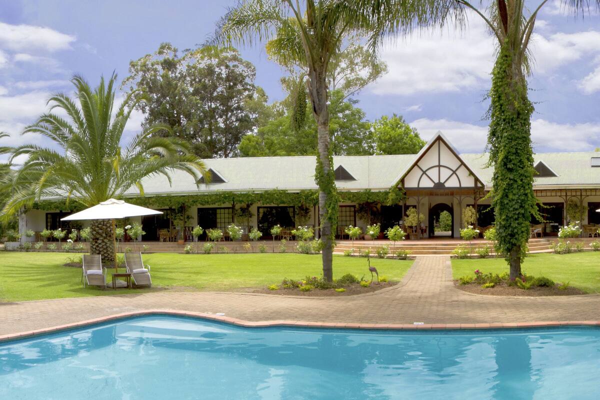 A poolside view of a resort with a large pool, lounge chairs, and a building with a covered patio area.