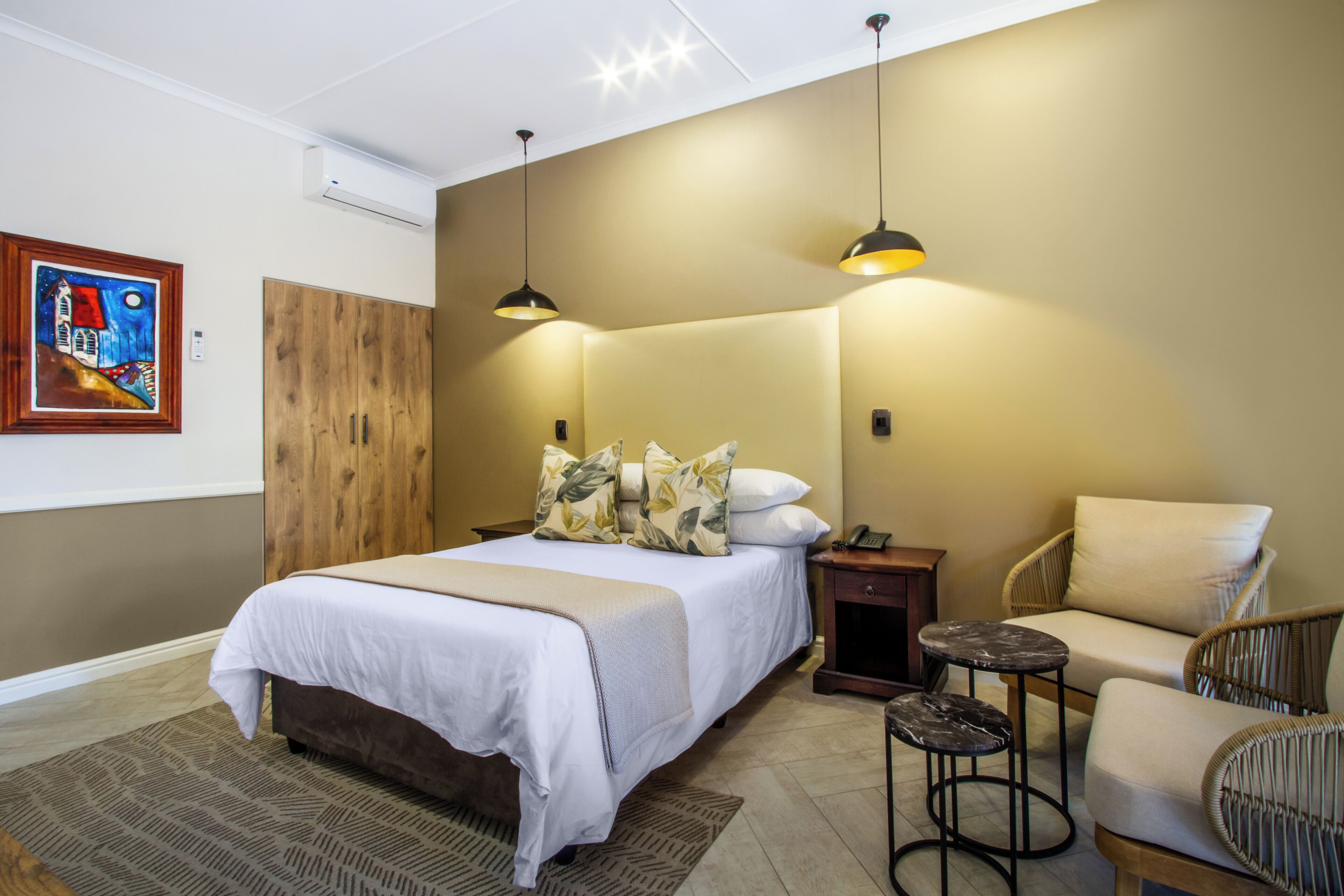 Une chambre à coucher comprenant un lit, deux tables de chevet, une chaise et une petite table.