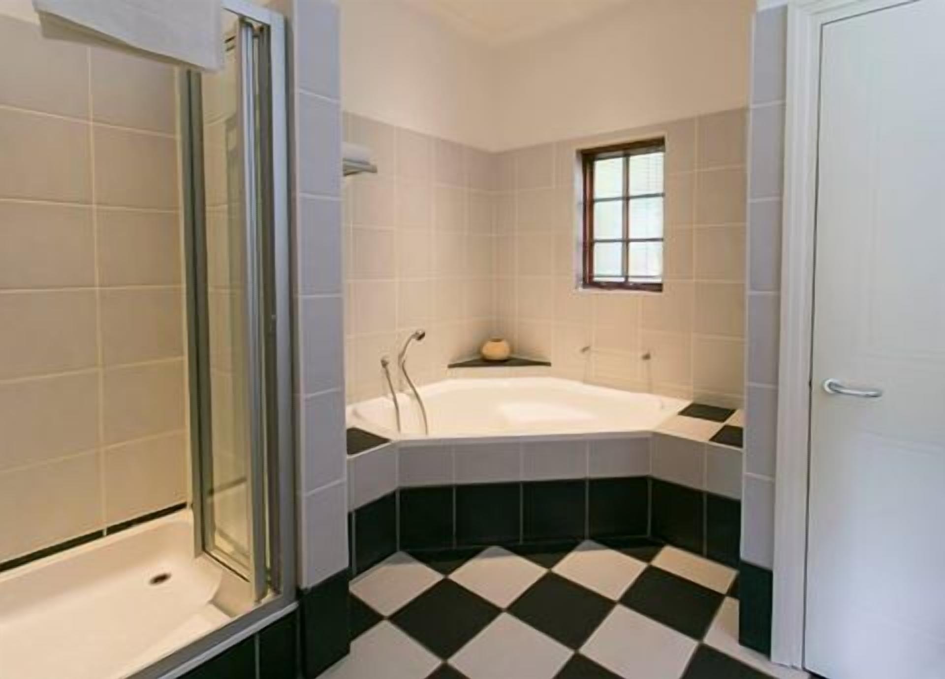 Une salle de bain avec une baignoire, une douche et une fenêtre.