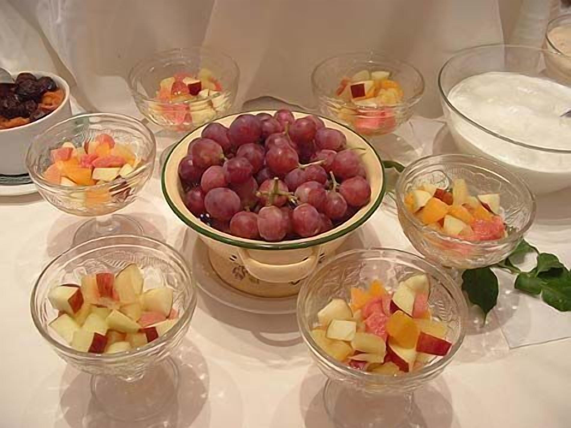 Una mesa con diferentes recipientes de fruta y un bol de yogur.