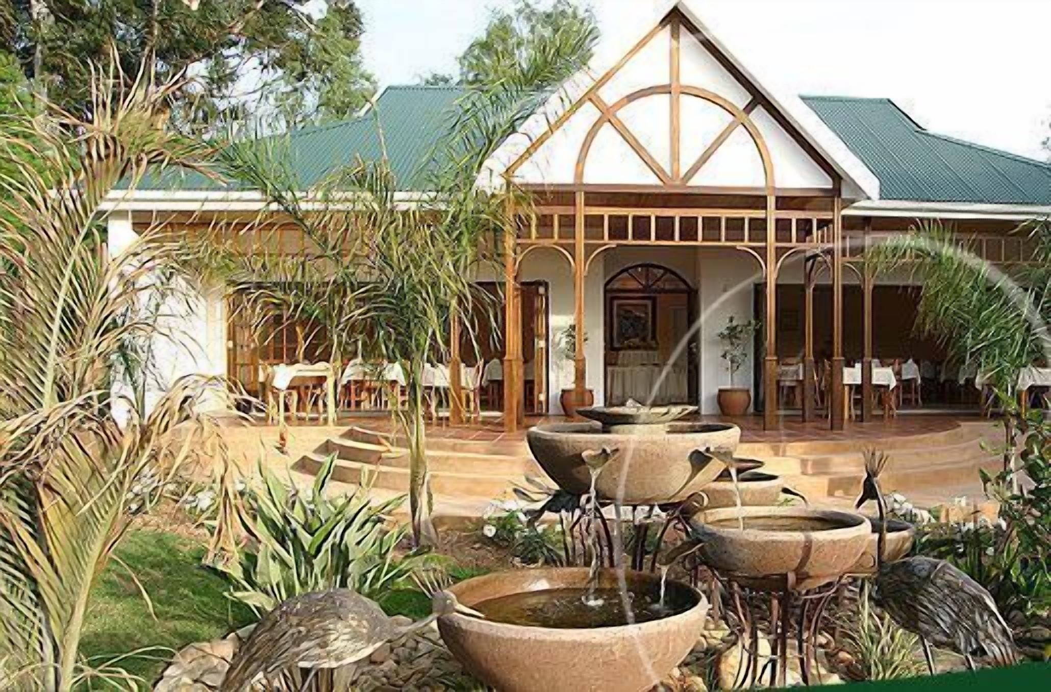 A building with a traditional architectural style, featuring a prominent arched entrance and a series of outdoor water fountains.