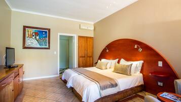 A bedroom with a large bed, a wooden headboard, a television on a wooden dresser, and a painting on the wall.