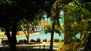 Zona de piscina con un puente, rodeada de árboles y una valla.