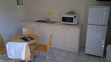 A small kitchenette with a microwave, refrigerator, sink, and a table with chairs.