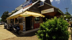 Un edificio con un letrero que dice 'Whitsunday On The Beach' y 'Holiday Units & Tour Bookings'. Hay un letrero que indica 'VACANCY', uno con 'Shute Harbour Road' y otro con 'LinksLiving'.