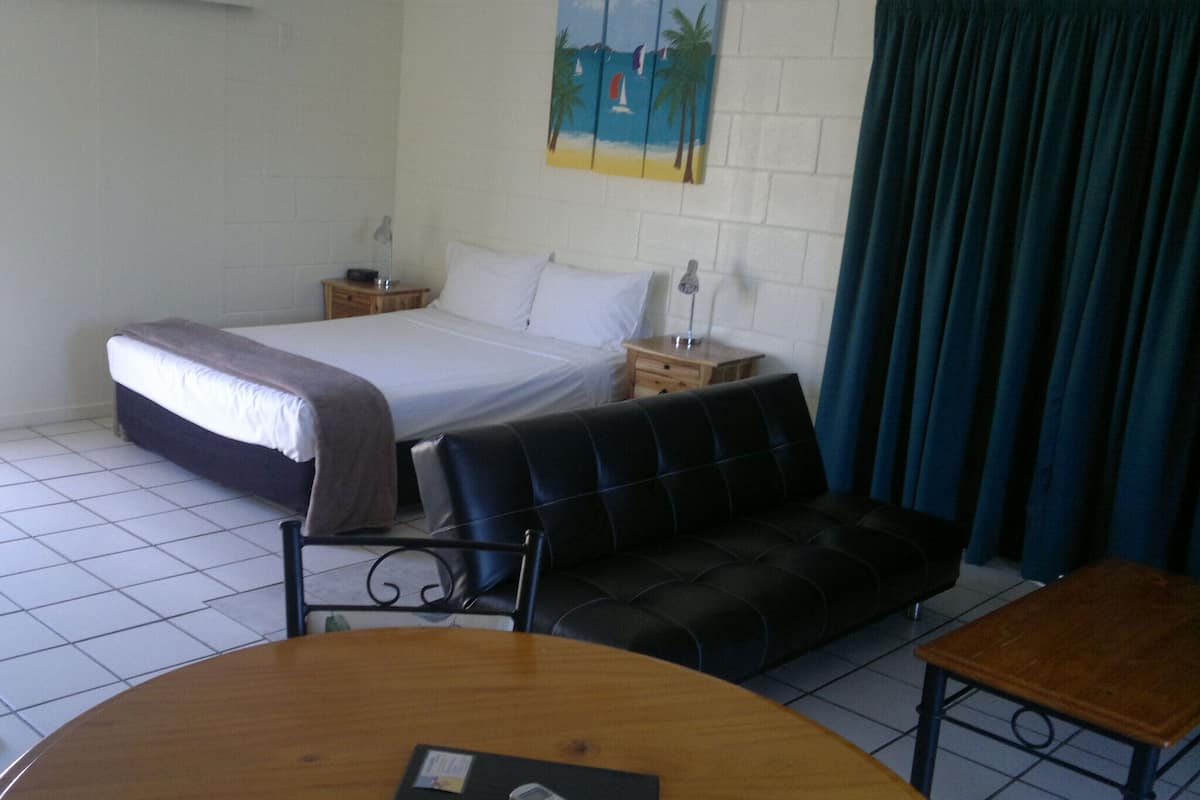 A hotel room with a bed, a sofa, a table, and a painting on the wall.