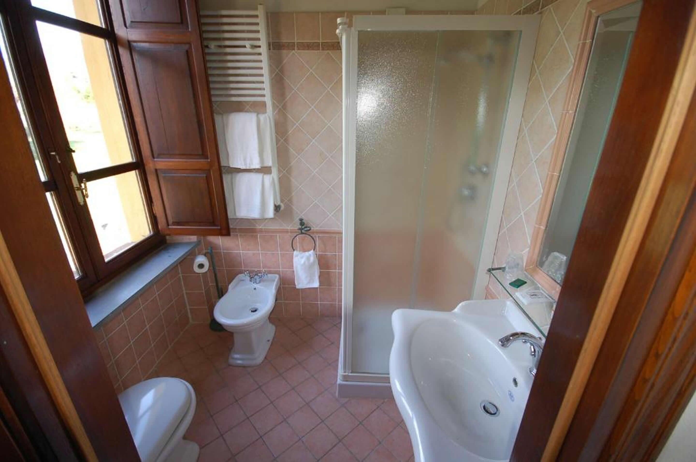 A bathroom with a toilet, bidet, shower, and sink.