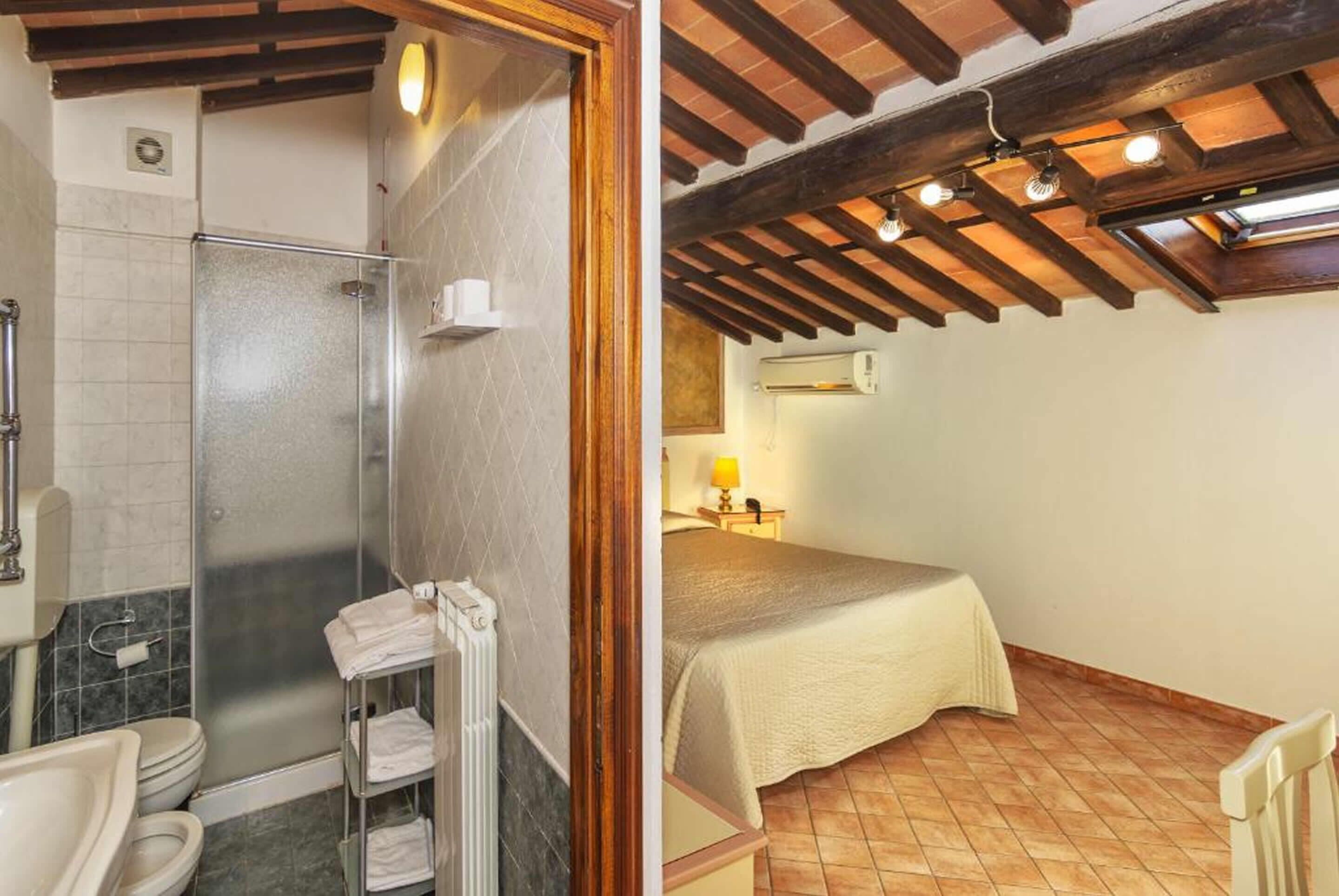A bathroom with a shower, toilet, and sink. The room has a tiled floor and a wooden ceiling.
