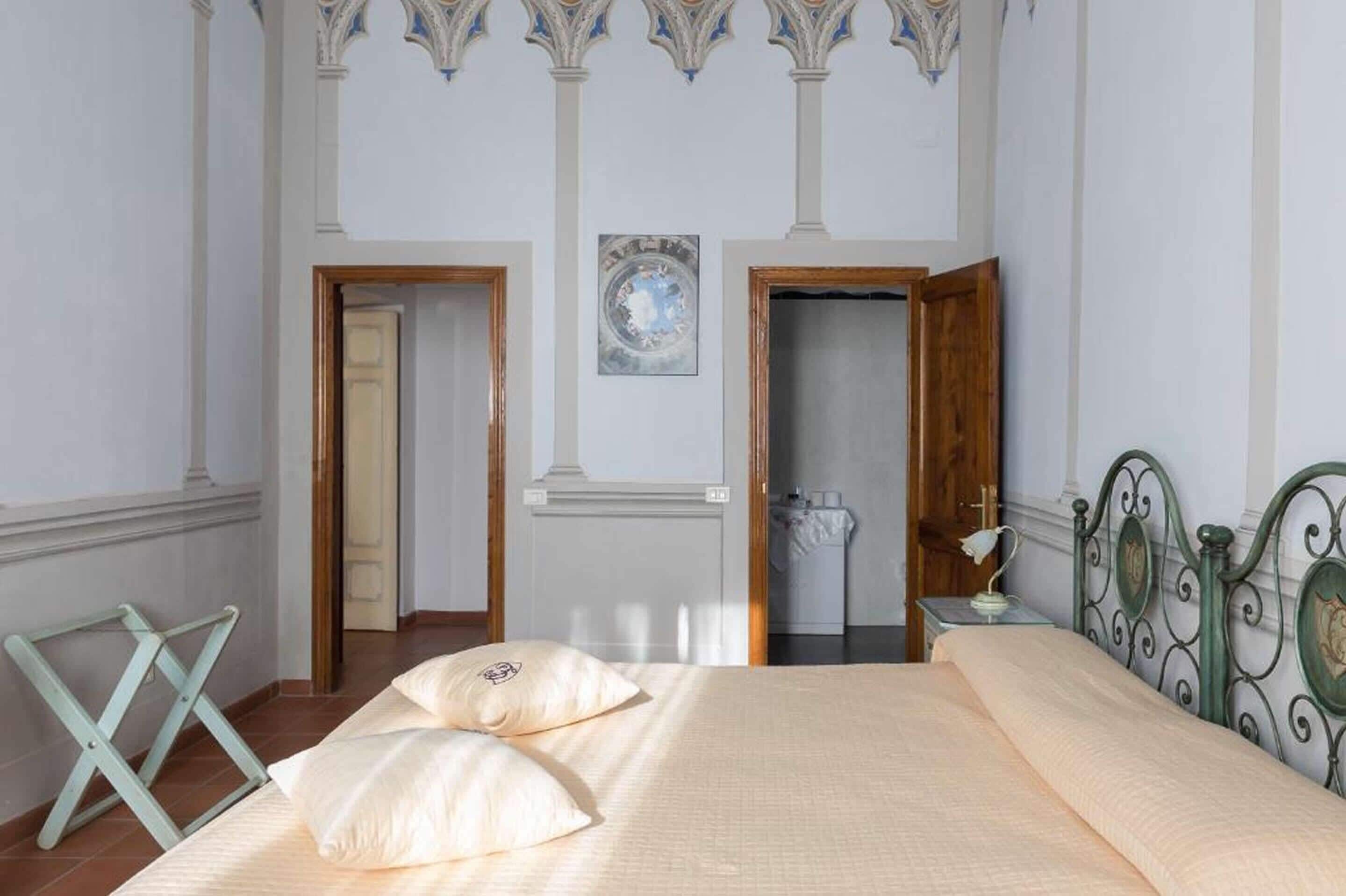 Un dormitorio con una cama, dos puertas, una mesita de noche con lámpara y un techo decorativo.