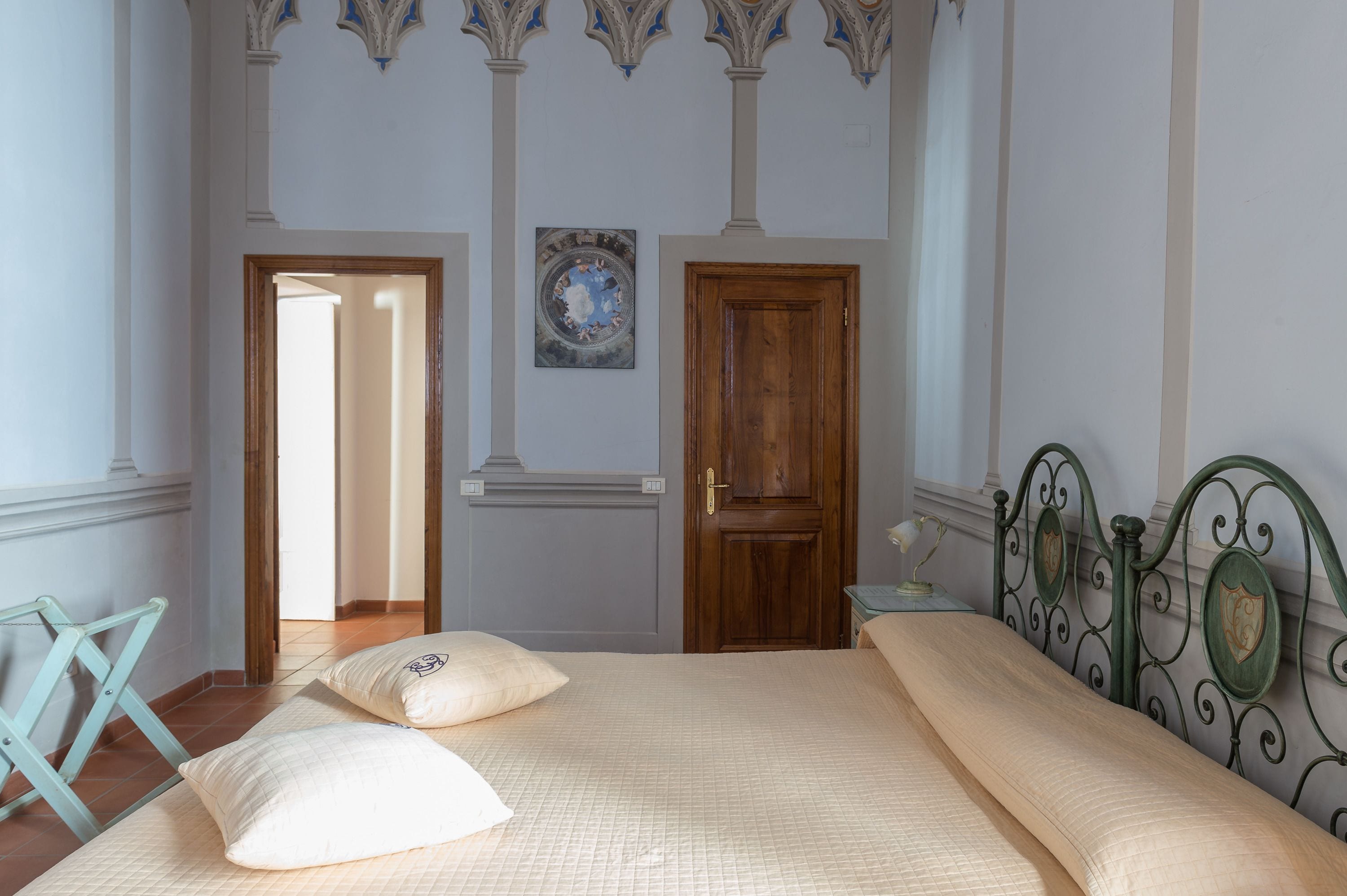 A bedroom with a bed, pillows, a wooden door, and a bicycle leaning against the wall.