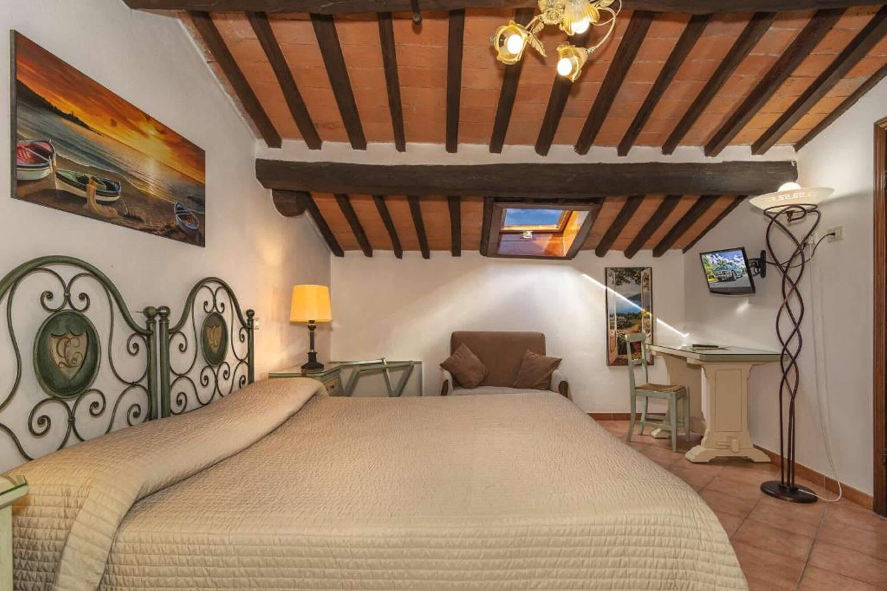 Une chambre à coucher avec un lit, un bureau, une chaise, une lampe, un téléviseur et un tableau représentant des bateaux.