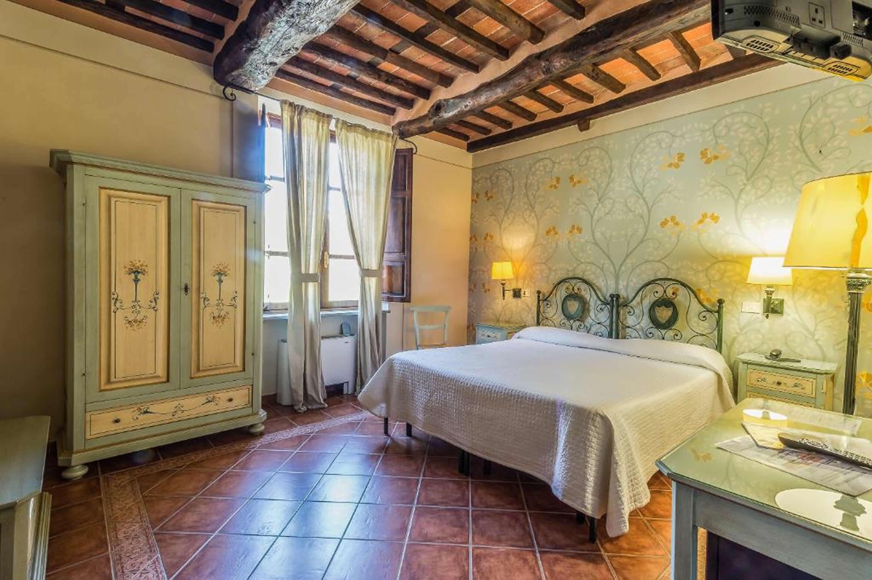 Un dormitorio con cama, mesita de noche, cómoda y ventana con cortinas.