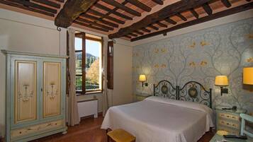 A bedroom with a bed, two bedside tables with lamps, a wardrobe, and a window with curtains.