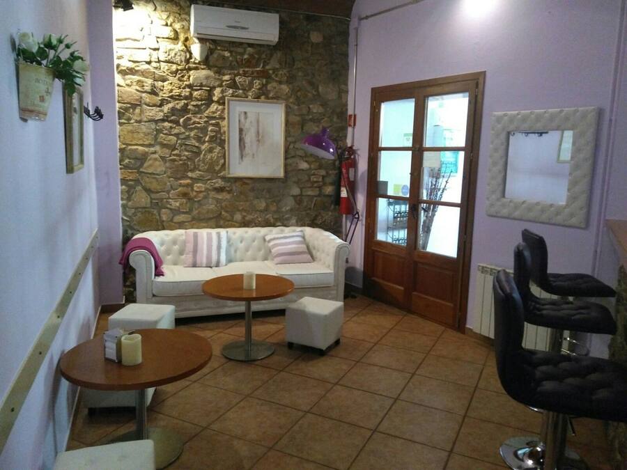 A cozy room with a stone wall, a white sofa, a small round table, a black chair, and a door with a glass panel.