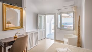 Un dormitorio con cama, escritorio, silla, televisor y vistas al exterior.