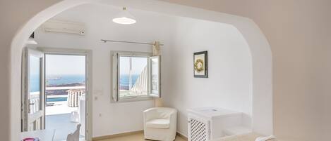 Een hotelkamer met een bed, een stoel, een bureau en uitzicht op zee.