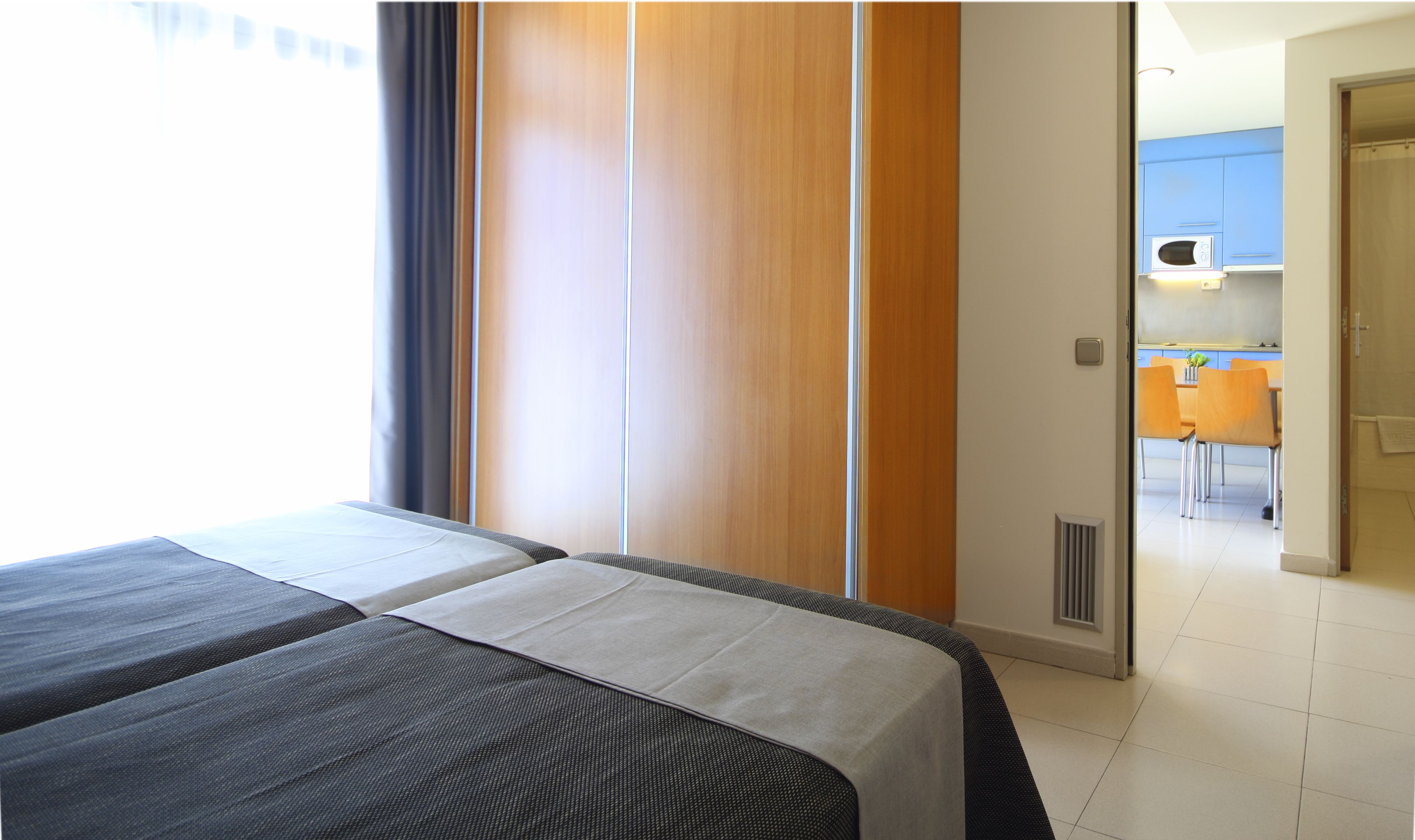 Habitación de hotel con dos camas, un separador de madera, vistas a la cocina y un comedor.