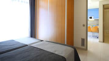 Habitación de hotel con dos camas, un separador de madera, vistas a la cocina y un comedor.