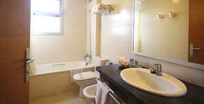 Une salle de bain avec une baignoire, des toilettes, un lavabo et un grand miroir.