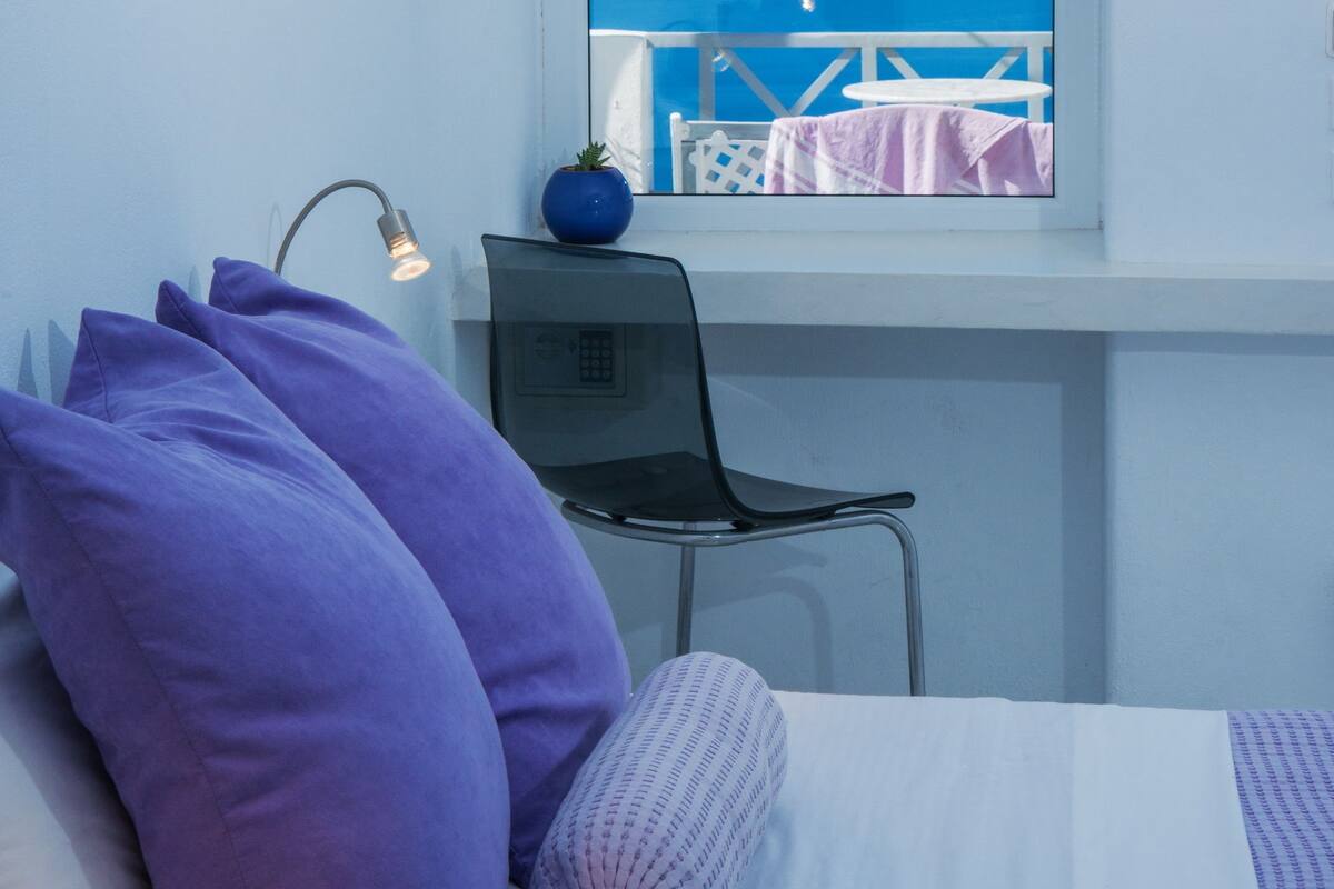 Una habitación con cama, escritorio y ventana con vista al mar.