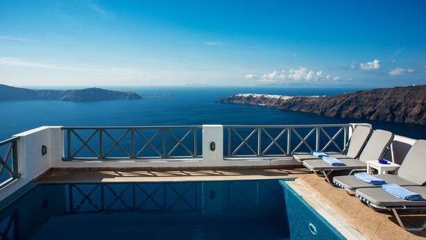 Zona de piscina con sillones de descanso y vista al mar y las montañas.