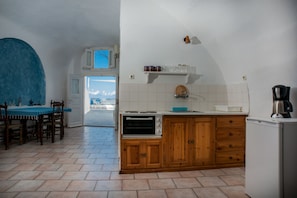 Una cocina con comedor, armarios de madera, horno empotrado y vistas a través de una puerta abierta.