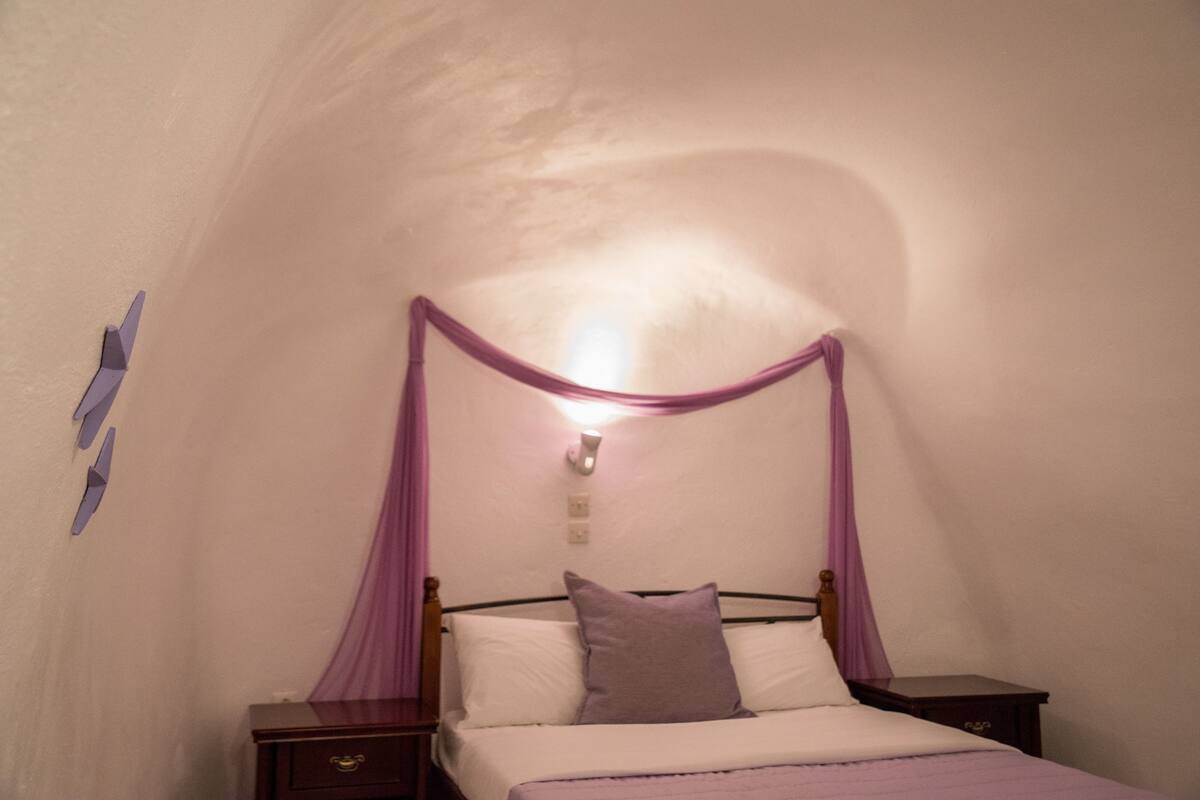 Un dormitorio con cama con dosel, una mesita de noche y una lámpara fijada a la pared.