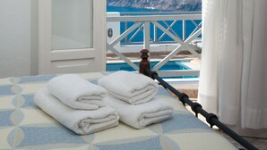 Una habitación con cama, ventana con cortinas y vistas a un paisaje montañoso.