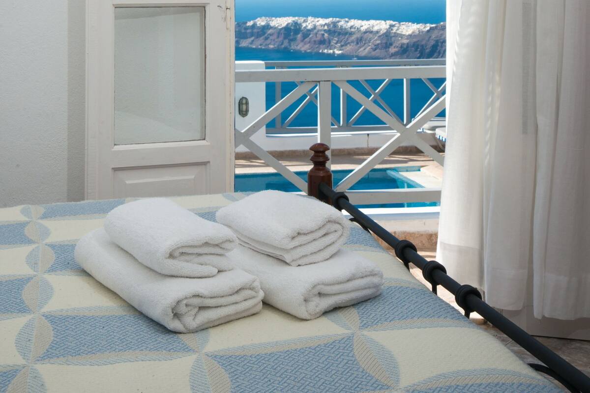 Una habitación con cama, ventana con cortinas y vistas a un paisaje montañoso.