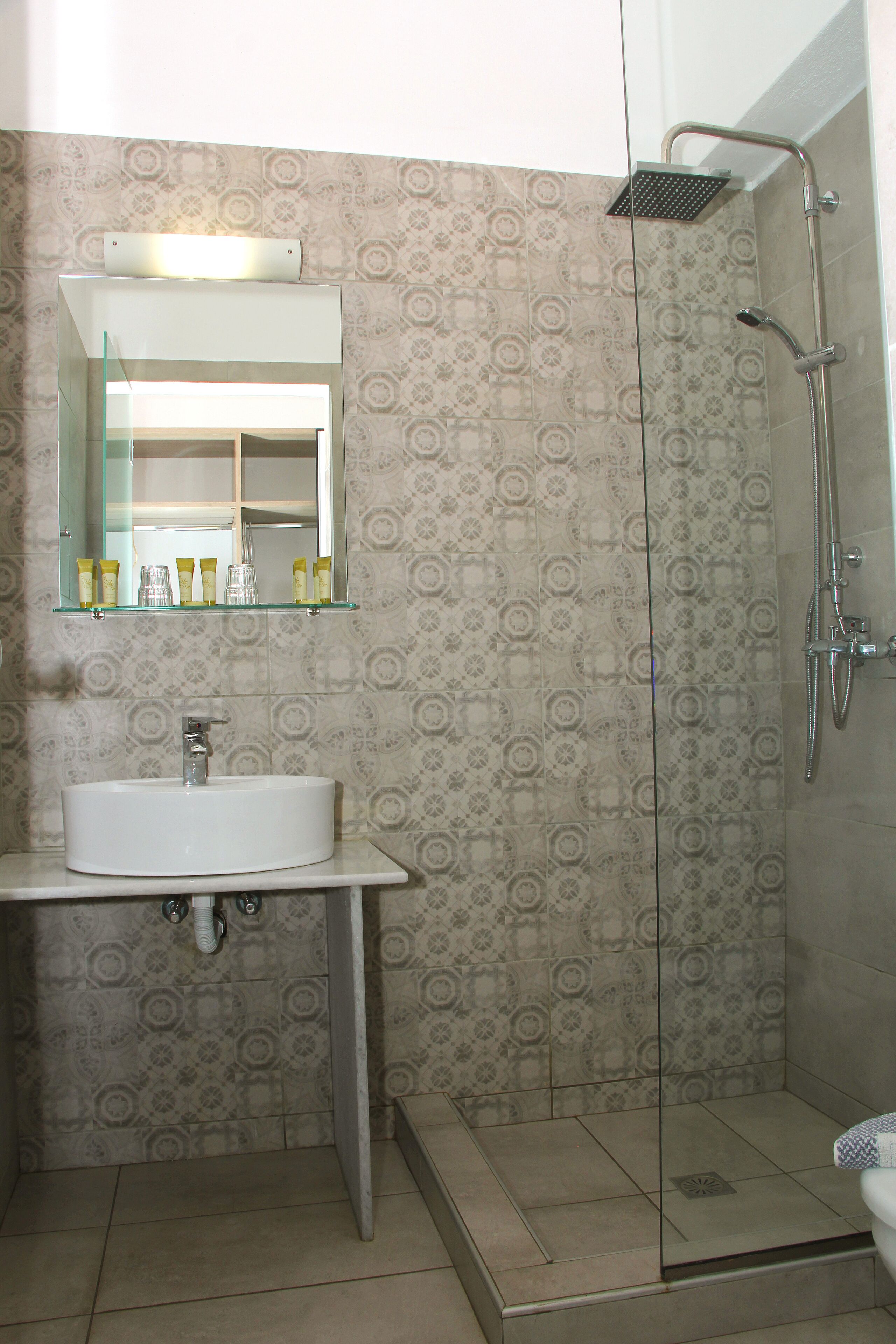 Une salle de bain avec une douche à parois de verre, un lavabo blanc et un miroir au-dessus du lavabo.