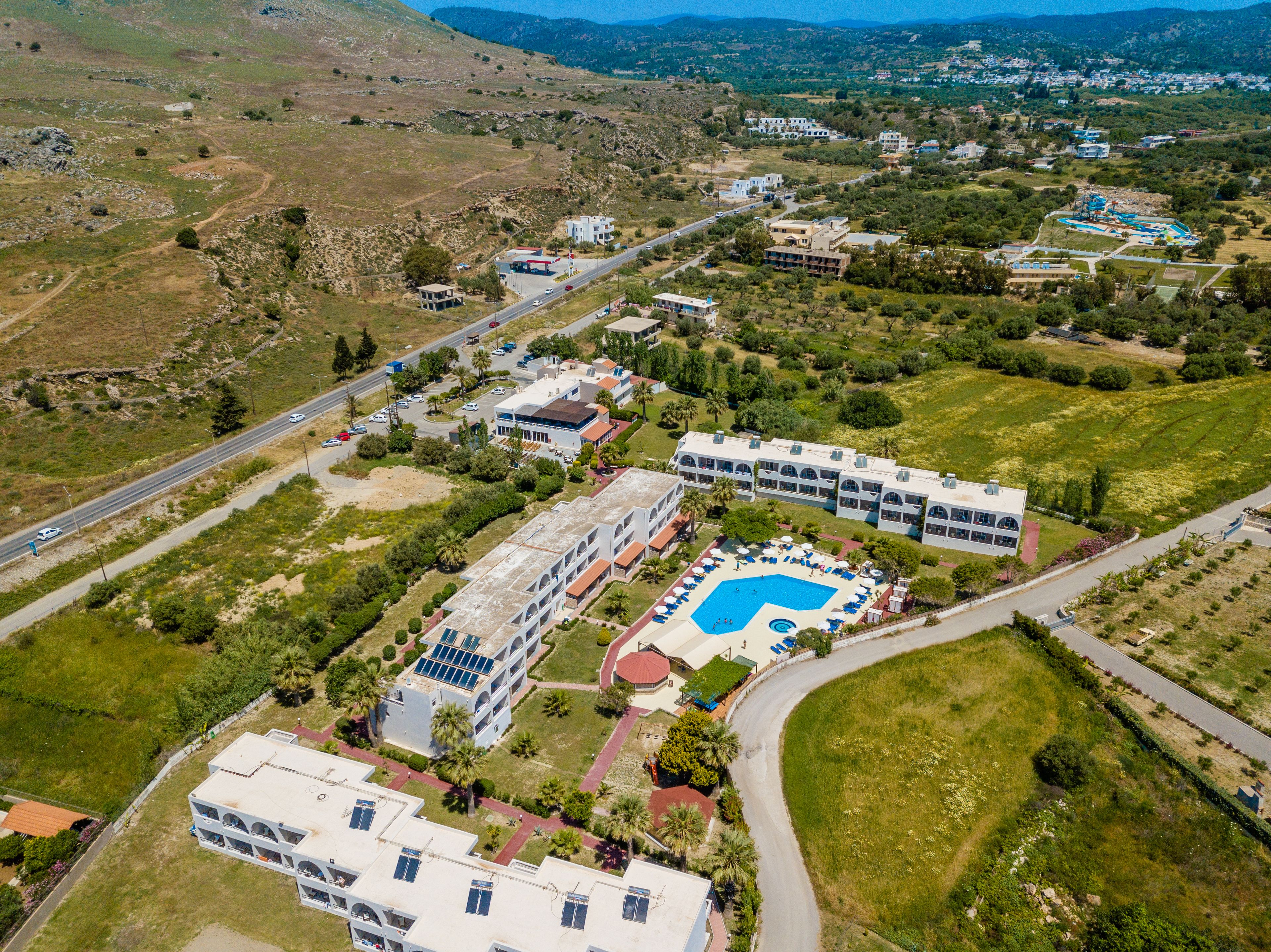 Vista aerea di un resort con diversi edifici, una piscina e vegetazione circostante.